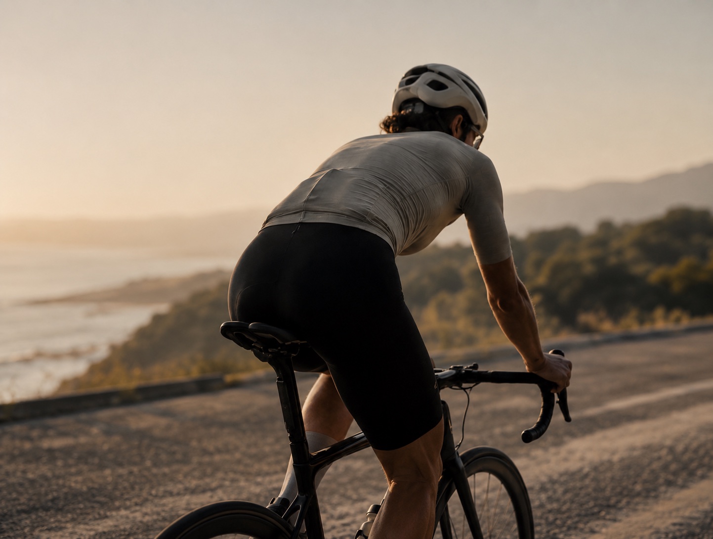 A cyclist climbing along the coast in evening light